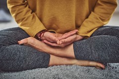 Closeup of persons hands and feet while meditating on gray carpet