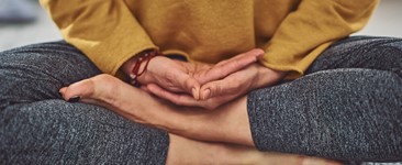 Closeup of persons hands and feet while meditating on gray carpet