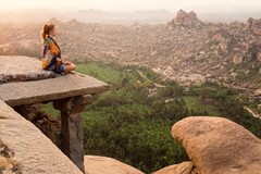 woman sitting on rock ledge overlooking jungle and mountains