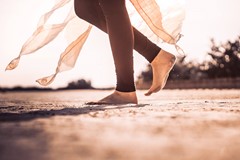 Lady in yoga legging walking across sand with bare feet