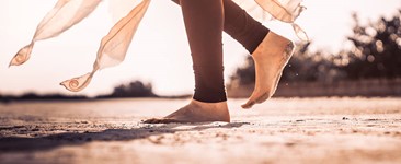 Lady in yoga legging walking across sand with bare feet