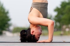 Side view of woman doing headstand on yoga mat
