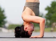 Side view of woman doing headstand on yoga mat