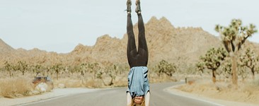 woman doing handstand in the middle of the road surrounded by joshua trees