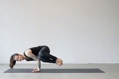 woman doing side crow yoga pose