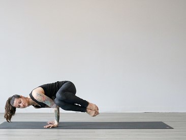 woman doing side crow yoga pose