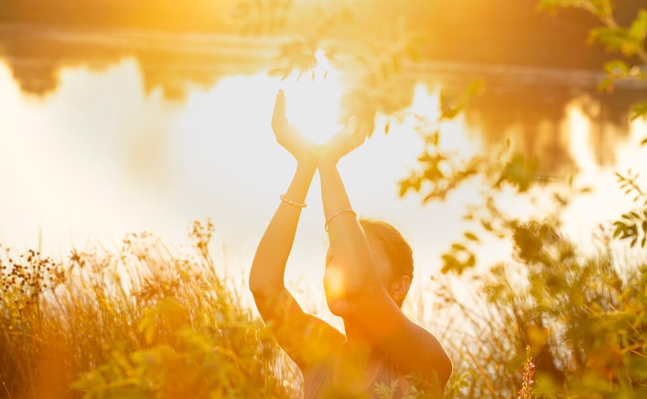 Woman hands in mudra at sunset on the lake in nature
